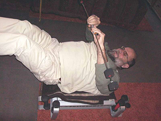 Stab waagrecht vor dem Oberkörper schwingen auf dem Posturomed liegend